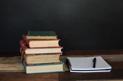 Small pile of books with notepad and pen